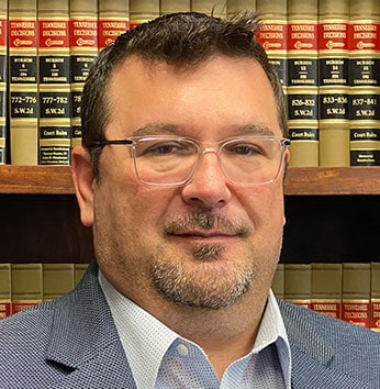 Image of Robert Maines, Esq., in front of a bookshelf filled with legal books. - Maines Legal