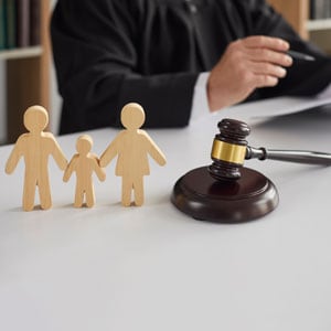 Judge with wooden family figures and gavel, representing family law and co-parenting in Tennessee - Maines Legal